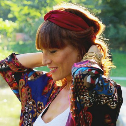 Une femme qui attache ses cheveux avec un headband rouge.