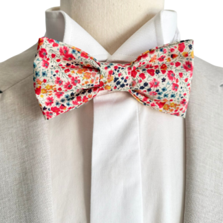 nœud papillon en tissu Liberty of London Phoebe aux motifs de petites fleurs roses, corail et jaunes. Création artisanale fait main en Provence pour un mariage bohème chic- sur costume beige