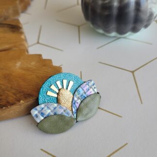 Broche fleur solaire en cuir réemployé turquoise kaki et ciel et rayons en plaqué or